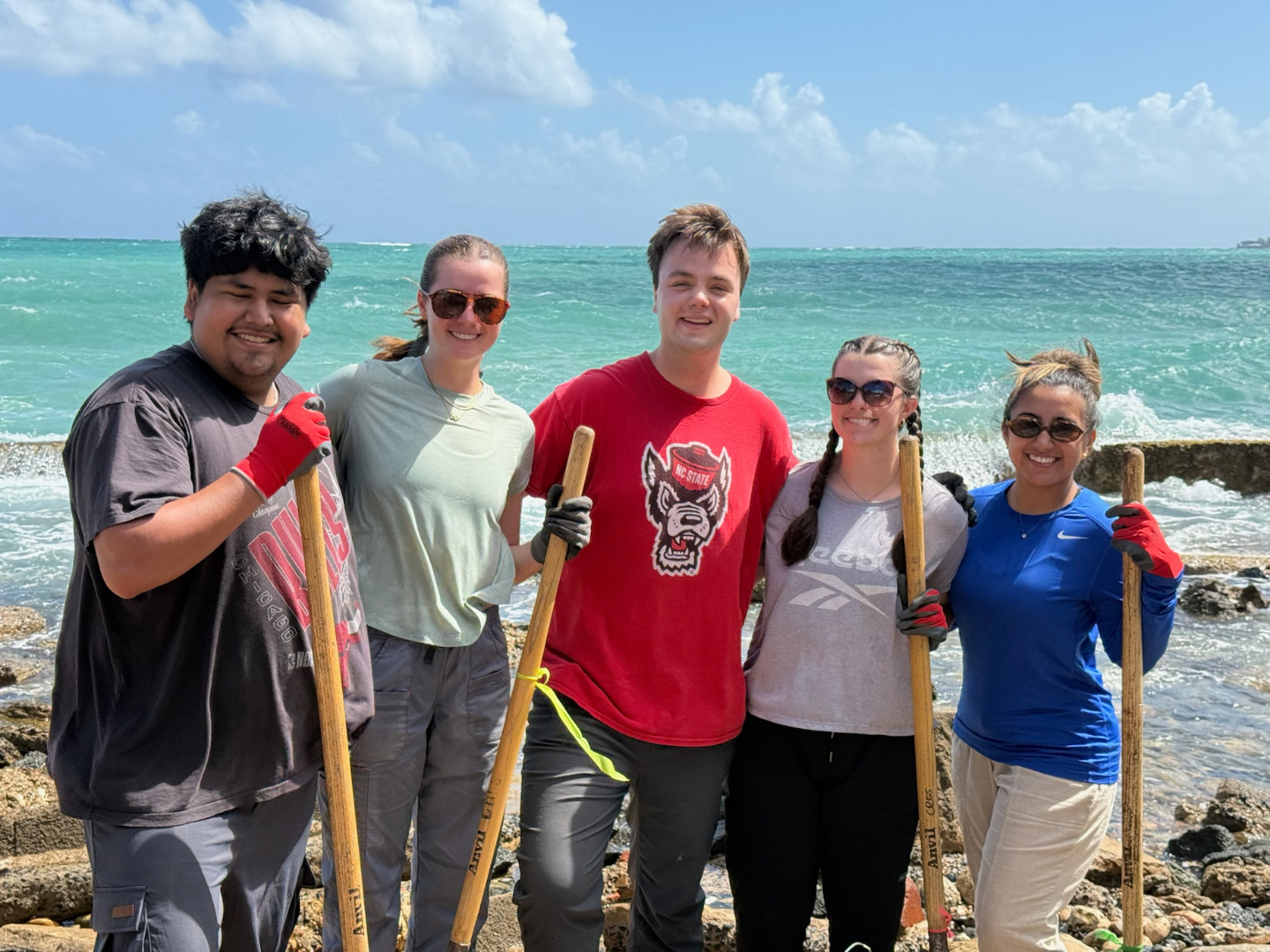 A group of ASB Puerto Rico participants pose for a photo at the worksite on a beach.