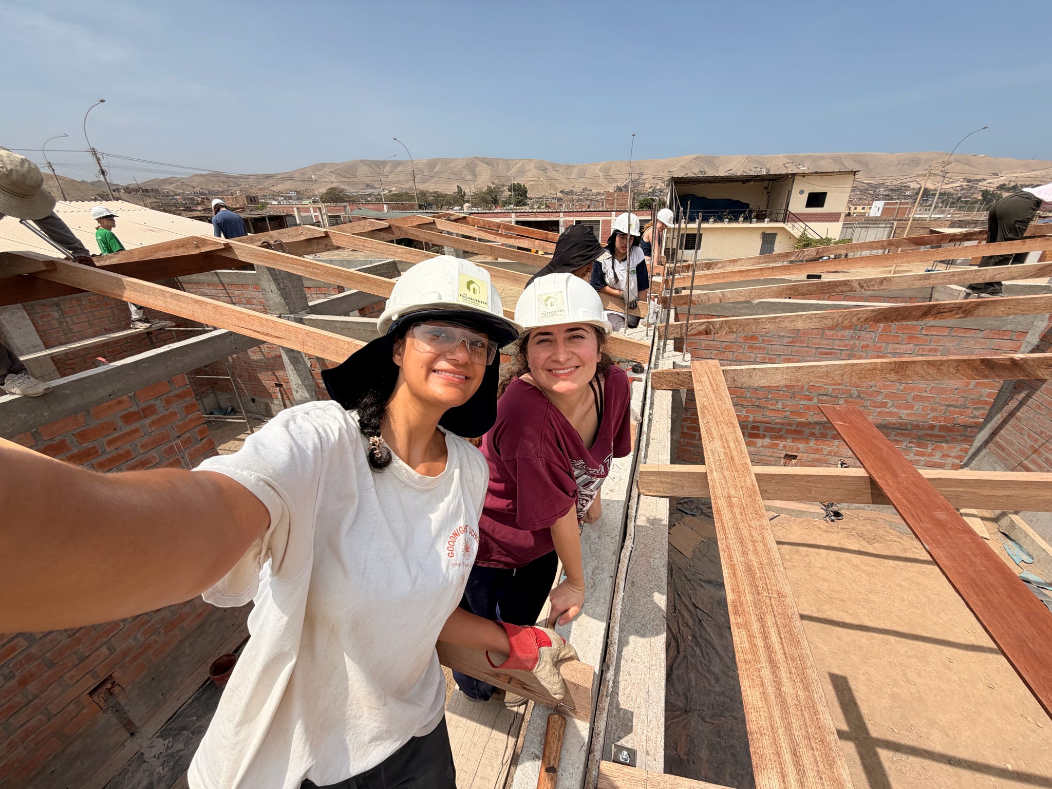 Two ASB Peru participants pose for a picture while working on a roof structure at the service site.