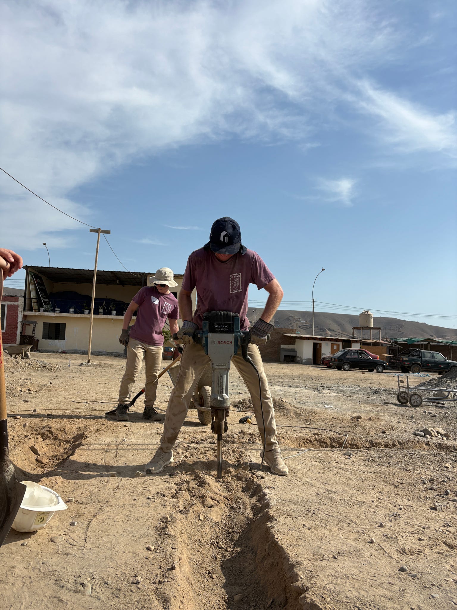 An ASB Peru participant uses a jackhammer to break up clay dirt at the service site.