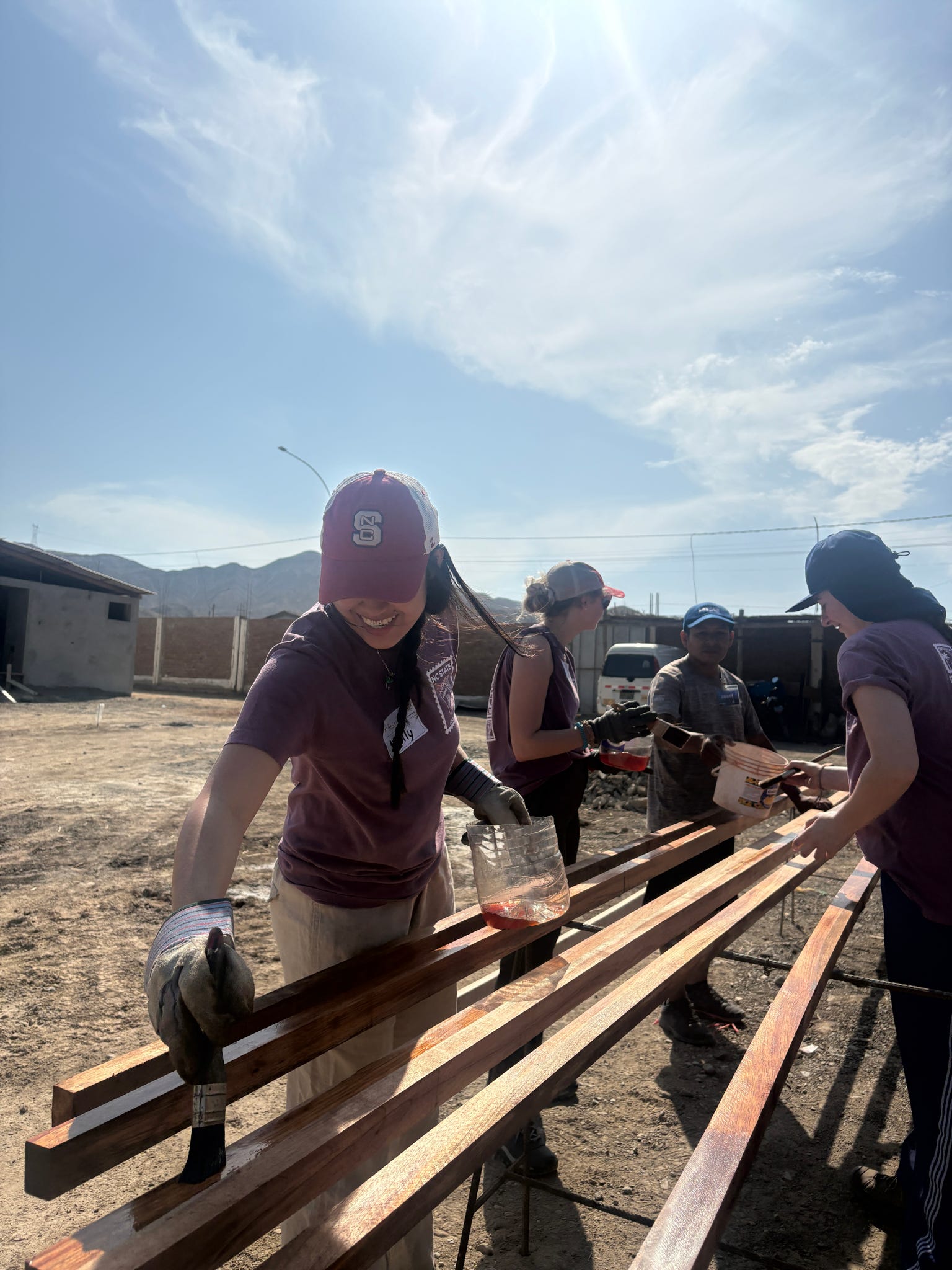 A ASB Peru participant treats and stain wood in preparation for construction of a house.